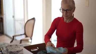 Olgun kadın kalıtsal porselen yemek takımlarını açar ve aile anılarını ve birlikte yemek yerken paylaştığı aşkı yansıtır..