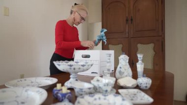 Olgun kadın kalıtsal porselen yemek takımlarını yerleştirirken aile yemeklerinin anılarını paylaşıyor ve tarihini araştırıyor..