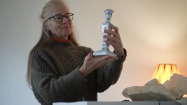 Olgun bir kadın, geçmişiyle ilgili anıları ve duyguları barındıran aile şamdanını ortaya çıkarmak için bir kutu açar..