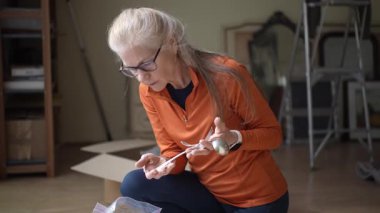 Olgun bir kadın ailesine ait gümüş çatal bıçakları inceler. Anıları, aile yadigarlarının ve mirasının önemini yansıtır..