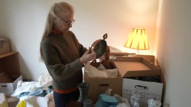 Olgun bir kadın, seyahat ve aile yadigârlarıyla dolu bir kutuyu açar. Anıları ve yaşam alanındaki bağlantıları barındırır..