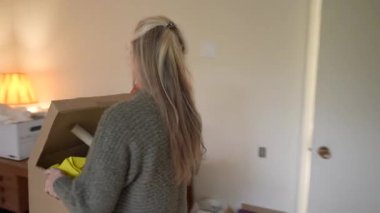 Olgun bir kadın, evindeki anılarını yad ederken bir kutu dolusu aile yadigârını ve aile yadigarlarını açıyor..