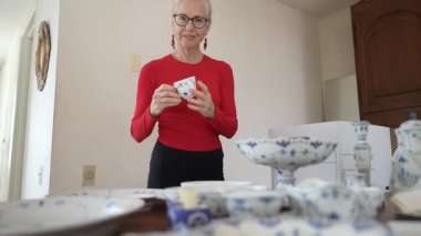 Olgun kadın miras kalan porselenleri açıyor ve aile yemeklerinden ve bu hazinelerle ilgili gelenek ve hikayeleri hatırlıyor..