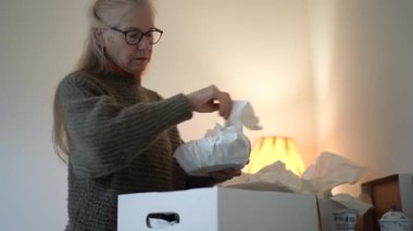 Olgun bir kadın, aile yadigarlarını açar ve akşam ışığında her bir parçayla ilgili anıları hatırlatır..