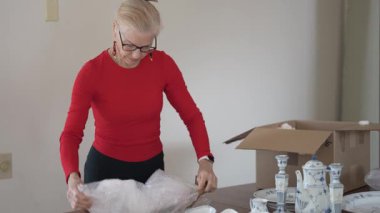 Olgun bir kadın antika porselen yemek takımlarını açar ve bu değerli eşyalar ve özel durumlarla bağlantılı aile anılarını hatırlar..