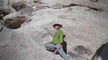 Olgun bir kadın gün batımında Joshua Tree Ulusal Parkı 'nda çöl patikalarını keşfederken doğal çevrenin ve yürüyüşün tadını çıkarıyor..