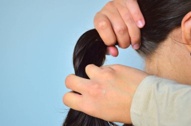 Arkasından çekilen bir fotoğraf sağlıklı, parlak siyah saçlardan oluşan şehvetli bir kesit topluyor. Saç yoğunluğu, güç ve profesyonel güzellik hizmetleri temaları yakalar