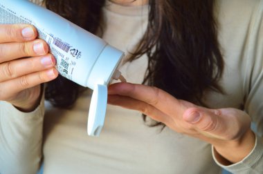 Kadın ellerinin tüp içinden avuç içlerine nemlendirici krem dağıttığı yakın plan. Günlük el bakımı, cilt bakımı ürün uygulaması ve kişisel hijyen konsepti