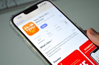 Bir akıllı telefondan TEMU uygulama sayfasını dinleyen bir elin yakın çekimi. Resim, Polonya 'daki çevrimiçi alışverişi, mobil e-ticareti ve TEMU platformu üzerinden Çin' den satın almaları gösteriyor..