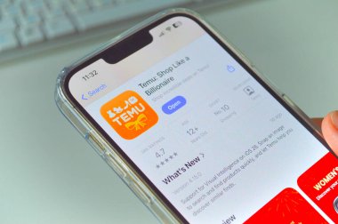 Bir akıllı telefondan TEMU uygulama sayfasını dinleyen bir elin yakın çekimi. Resim, Polonya 'daki çevrimiçi alışverişi, mobil e-ticareti ve TEMU platformu üzerinden Çin' den satın almaları gösteriyor..