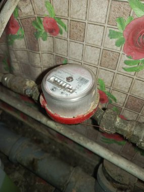 Rudny, Kazakistan - 10 Kasım 2025. Banyodaki borunun üzerindeki su sayacı. Soğuk ve sıcak su tüketimini kontrol ediyorum. Su fiyatlarında artış