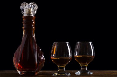 Bir şişe brendi ve ahşap bir masa üzerinde iki bardak