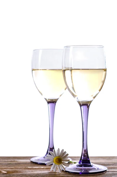 Dos copas de vino blanco sobre una mesa de madera con una manzanilla — Foto de Stock