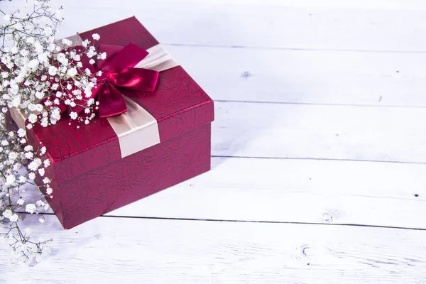 gift box and white flowers on white wooden background