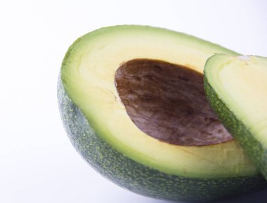 Beyaz arka planda iki dilim avokado izole edilmiş.