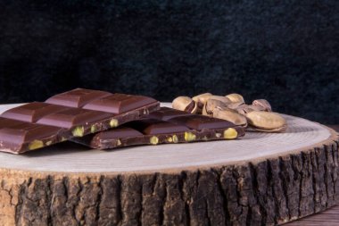 Tahta sehpanın üzerinde çikolata ve fıstık, ahşap zemin