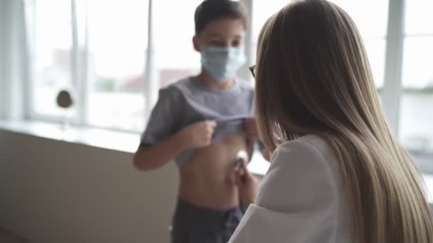 Médico pediatra mujer uniforme celebrar estetoscopio chequeo anual hasta niño pequeño mediante el control de la frecuencia cardíaca. Concepto sanitario. — Vídeos de Stock