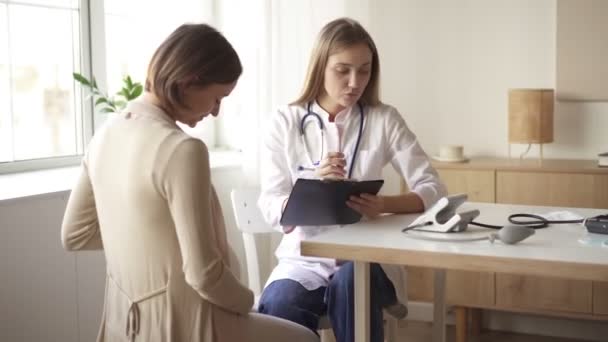 Mujer embarazada feliz visita médico ginecólogo en el hospital o clínica médica para el consultor de embarazo. El médico examinará el vientre del bebé y la madre embarazadas para verificar la atención médica. Concepto ginecológico. — Vídeos de Stock