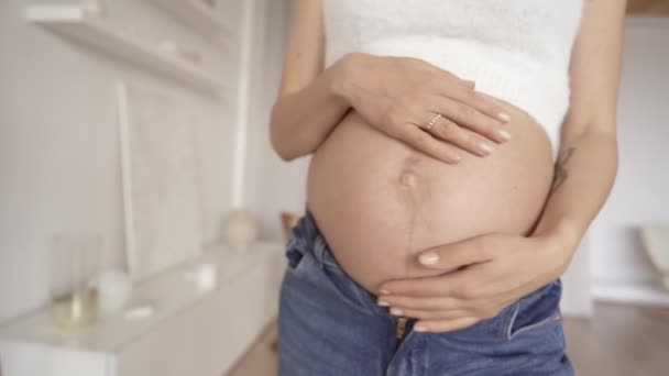 Тело беременной женщины с помощью скотча проверяют развитие ребенка, светлый интерьер дома, здоровье и самочувствие. Здоровье благополучия беременность образ жизни — стоковое видео