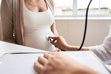 Doktor, klinikte hamile bir kadını muayene etmek için el ele tutuşuyor. Doktor, sekiz aylık hamile olup olmadığını kontrol et..