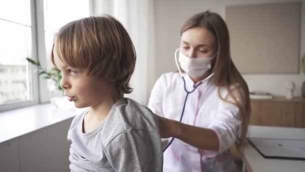 Kinderarts arts vrouw uniform houden stethoscoop jaarlijkse check-up peuter jongen door het controleren van de hartslag. Gezondheidszorgconcept. — Stockvideo