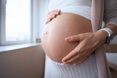 Hamile kadın ellerini şişmiş karnında tutuyor..