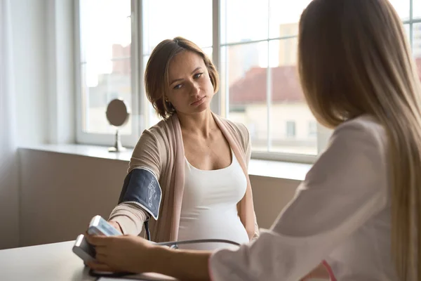 Doktor hamile hastasının kan basıncını ölçüyor.