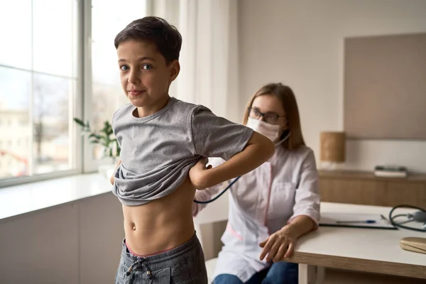 Çocuk doktorunu ziyaret eden tatlı bir çocuk, bebek sağlığı kontrolü, aile doktoruyla randevu, sağlıklı yaşam tarzı. 