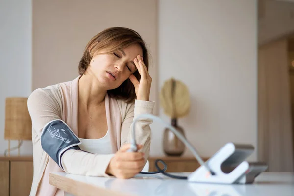 Hamile kadın elektronik tonometreyle kan basıncını ölçüyor. Hamilelik sırasında nevralji, kötü sağlık. Yüksek tansiyon. Ağır hamilelik. Baş ağrısı, migren..