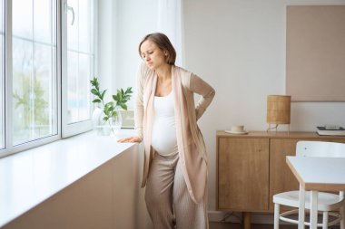 Sağlık hizmeti, tedavi. Sırtında ani bir ağrı hisseden hamile bir kadın. Müstakbel anne sırt ağrısı çekiyor..