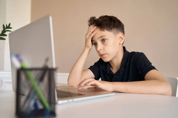 Akıllı çocuk ödevini yapıyor ve Covid-19 salgını ve sosyal mesafesi yüzünden evdeki bilgisayar defterine bakıyor..