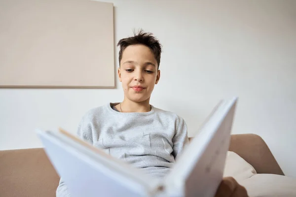 Beyaz çocuk evde kitap okuyor.