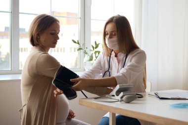 Doktor hamile hastasının kan basıncını ölçüyor.