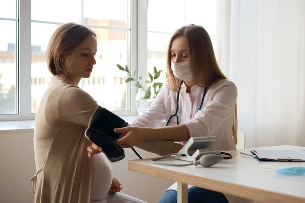 Doktor hamile hastasının kan basıncını ölçüyor.