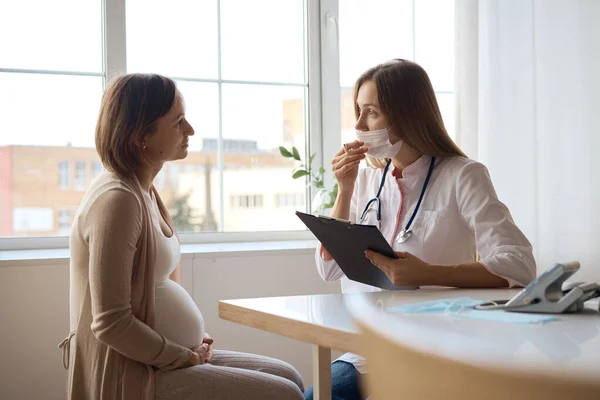 Wanita hamil yang bahagia mengunjungi dokter kandungan di rumah sakit atau klinik medis untuk konsultan kehamilan. Dokter memeriksa perut hamil untuk pemeriksaan kesehatan bayi dan ibu. Konsep ginekologi. — Stok Foto