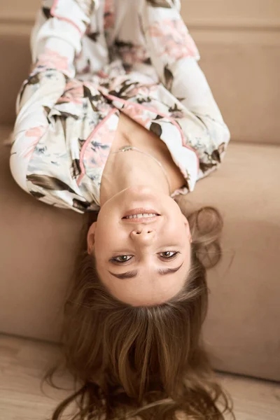 Meisje in witte zijde pyjama liggend op de bank thuis — Stockfoto