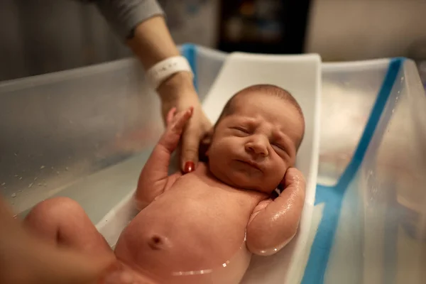 Pequeno bebê primeiro banho nas mãos da mãe, banho em pequeno banho de plástico — Fotografia de Stock