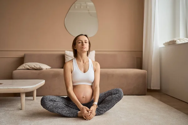 Potret wanita hamil muda yang duduk di atas tikar yoga menonton latihan tutorial di rumah, menyalin ruang — Stok Foto