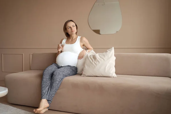Wanita hamil minum air di ruang tamu — Stok Foto