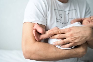 Baba yeni doğan çocuğun kolunu tutuyor.