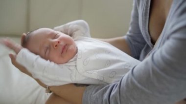 Mutlu genç anne yeni doğmuş bebeğini kollarında tutuyor.