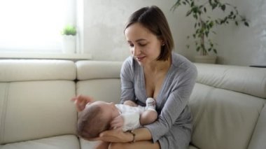 Mutlu genç anne yeni doğmuş bebeğini kollarında tutuyor.