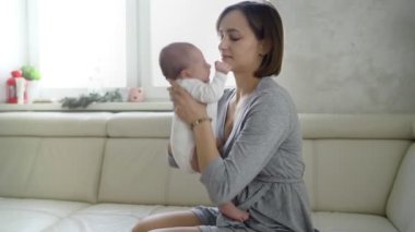 Mutlu genç anne yeni doğmuş bebeğini kollarında tutuyor.