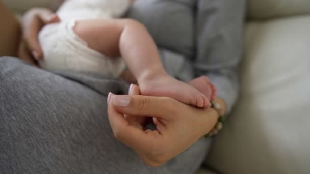 Närbild skott av mor sitter på soffan hemma och amning baby — Stockvideo