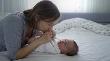 Evde küçük bir kızı olan güzel bir anne. Güzel bebeğiyle yakın plan portresi olan kadın birlikte eğleniyor ve eğleniyor. Çocuk olarak doğuyor ve mutlu bir şekilde gülümsüyor.