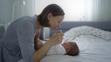 Evde küçük bir kızı olan güzel bir anne. Güzel bebeğiyle yakın plan portresi olan kadın birlikte eğleniyor ve eğleniyor. Çocuk olarak doğuyor ve mutlu bir şekilde gülümsüyor.