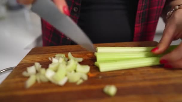 Mujer corta apio en una tabla de cortar para cocinar ensalada de verduras casera — Vídeos de Stock