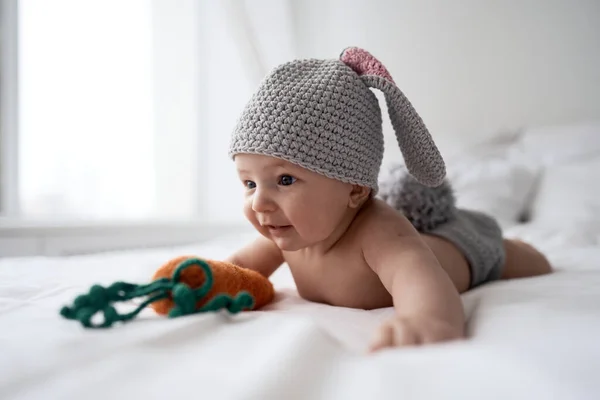 토끼 코스튬을 입고 하얀 침대에 누워 있는 생후 4 개월된 아기 — 스톡 사진