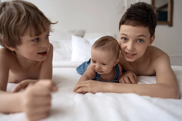 Tiga saudara laki-laki lucu berbaring di tempat tidur dan bersenang-senang — Stok Foto