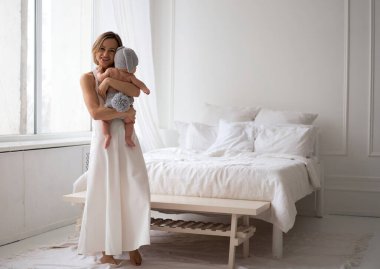 Beyaz elbiseli anne tavşan kostümlü bir çocuğu tutuyor ve onunla oynuyor.